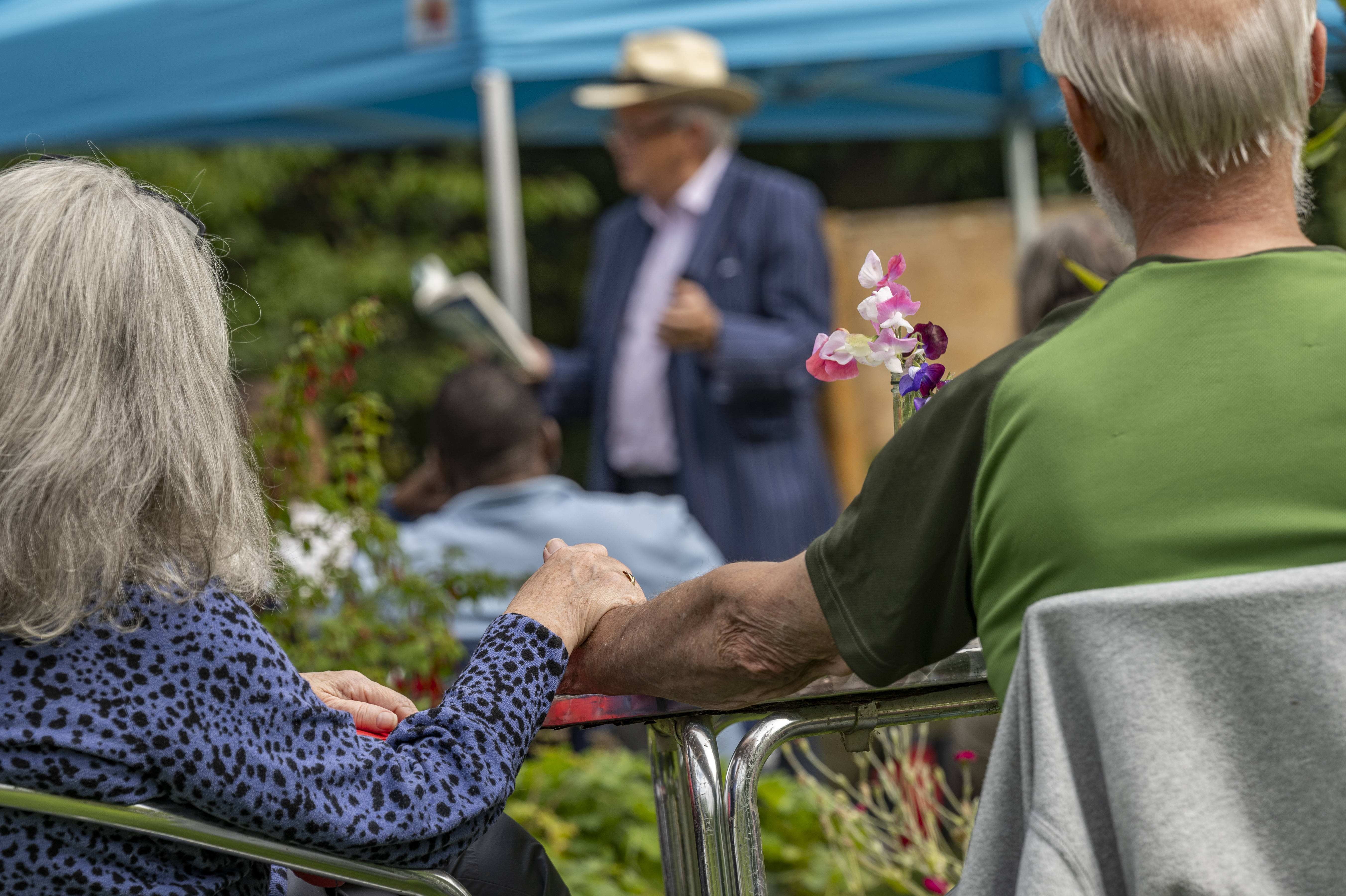 Two attendees at the Spring Fling hold hands as Alexander McCall Smith reads a poem (photo: Phil Wilkinson 2023)