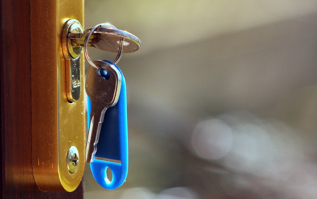 House keys with a blue tag sitting in a lock