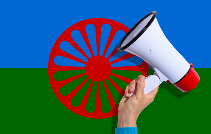 A Traveller flag overlaid with a hand holding a megaphone