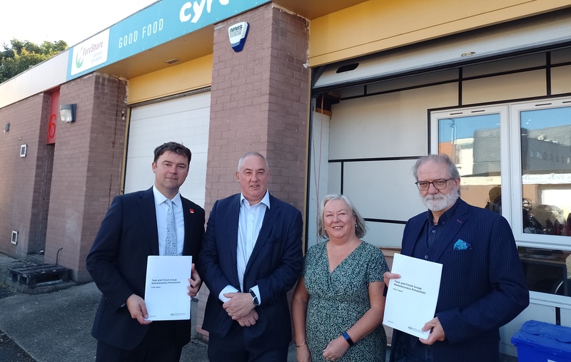 Crisis CEO Matt Downie, Housing Minister Paul McLennan, Councillor Maureen Chalmers, and Cyrenians CEO Ewan Aitken launch the new final report from the Homelessness Prevention Task and Finish Group, posing outside the Cyrenians Cook School with copies of the report.